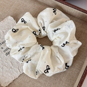 Detailed macro view of white scrunchie with black bow print and sparkling rhinestones