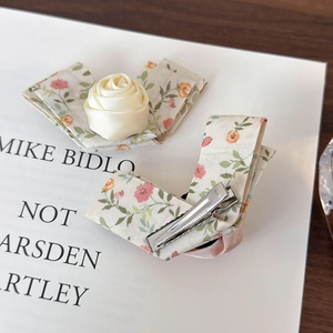 Detail view of floral fabric hair clip set with handmade satin rose on wooden surface