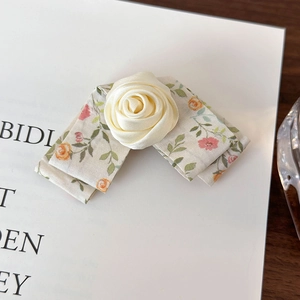 Detail of floral bow hair clip with a satin rose on a minimalist decorative card