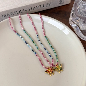 Colliers pendentifs papillon en émail avec chaînes de perles colorées dans un plateau