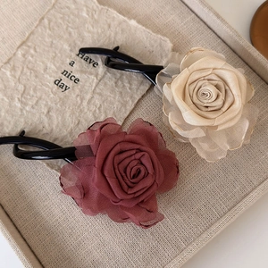 Detail of handmade champagne and rose red chiffon flower hair clips on beige linen background