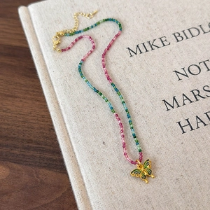 Détail d'un collier de perles colorées avec pendentif papillon doré sur livre