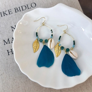 Detail of Bohemian earrings with blue feathers, metal leaves and natural shells