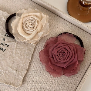 Macro shot of apricot and dark rose organza hair ties in a textured beige tray