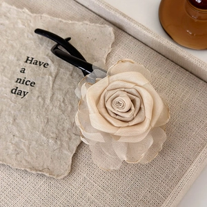 Close-up of handmade champagne rose hair clip on an aesthetic textured paper card