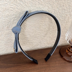 Close-up of blue denim bow headband with orange stitching and black non-slip teeth detail