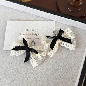 Détail de breloques en dentelle pour chaussures avec ruban noir et fermoir argent