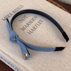 Close-up of blue denim bow headband featuring yellow topstitching and gold rivet detail
