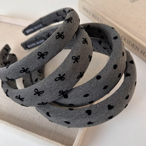 Detailed view of gray velvet padded headbands with heart, dot, and bow patterns