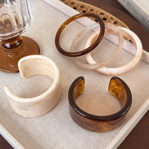 Collection of irregular acetate bangles in amber and marble patterns on a fabric tray