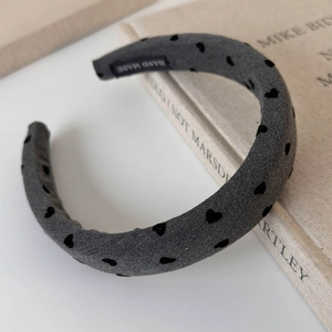 Close-up of handmade grey fabric headband with black flocked heart patterns