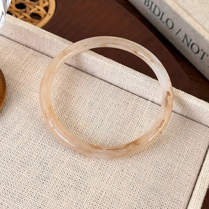 Macro view of amber patterned acrylic resin bangle with vintage marble texture on linen tray