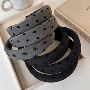 Close-up of gray and black sponge headbands with polka dots and bow details