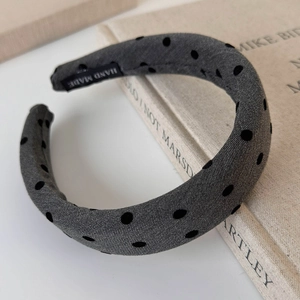 Detail of grey polka dot padded headband resting on a vintage book with handmade label
