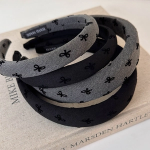 Detailed view of handmade flocked headbands with elegant black bow embroidery and labels