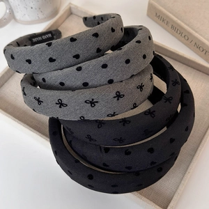 Detail of gray and black sponge headbands with heart and dot patterns and handmade label