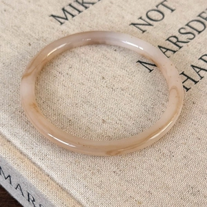 Close-up of marble-pattern acetate resin bangle with amber texture on a fabric book