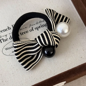 Detailed close-up of a striped bow hair scrunchie with white pearl and black bead accents