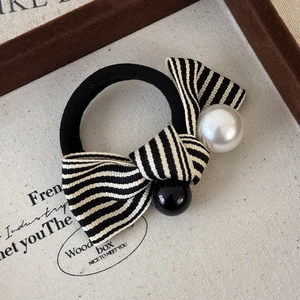 Close-up of black and white striped bow hair tie with faux pearl and black bead