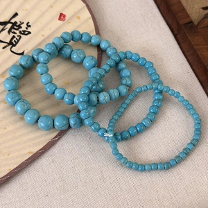 Lot de quatre bracelets en perles style turquoise bleue avec veinures brunes sur du lin