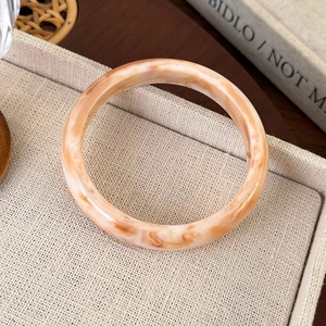 Macro detail of tortoiseshell acetate bangle with vintage orange marble pattern