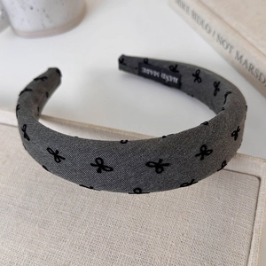 Detail of grey padded headband featuring black embroidered bows and handmade label