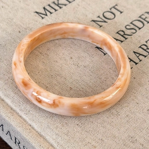 Detailed macro view of irregular acetate bangle with cream and amber marble texture