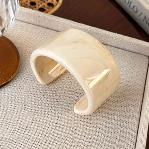 Detailed view of an irregular marbled acrylic cuff bangle with retro cream textures