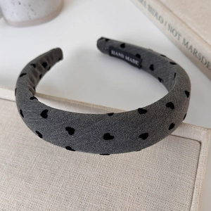Macro shot of gray twill headband featuring black flocked hearts and handmade label
