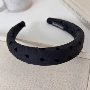 Detail of black padded headband with velvet hearts and handmade label on fabric