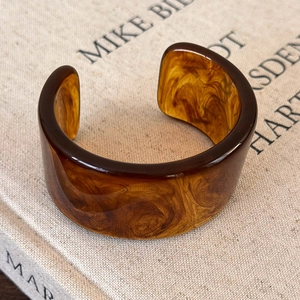 Detailed view of irregular acrylic cuff bracelet with brown marble and amber patterns
