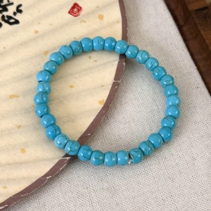 Détail d'un bracelet en perles bleues avec texture turquoise sur un éventail plié