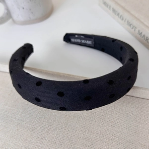 Detail showing handmade fabric headband with classic black velvet polka dots and woven label