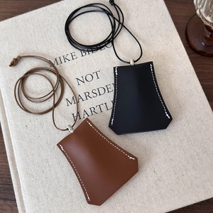 Detail of leather key case necklace pendants with contrast stitching on vintage book