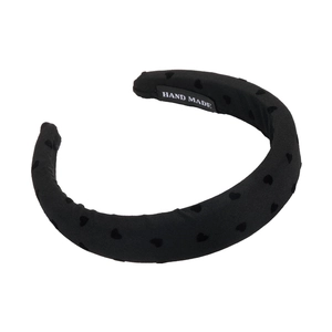 Padded black fabric headband featuring a subtle heart pattern with a hand-made label