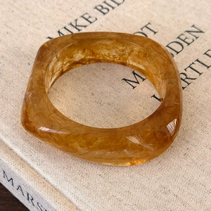 Macro shot of an amber acrylic ring with marble texture on a linen fabric book cover