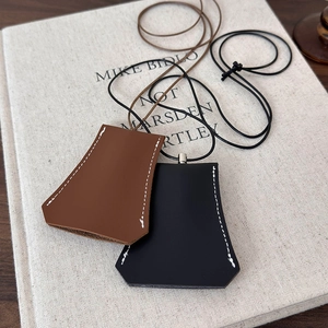 Close-up of leather clochette pendants with contrast stitching on a textured background