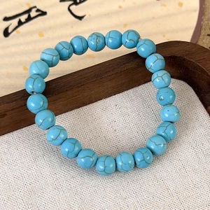 Vue détaillée des perles bleu ciel à texture craquelée sur un coussin de présentation