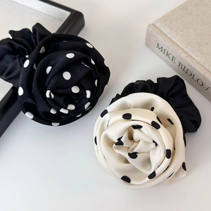 Vue détaillée des chouchous roses à pois en tissu satiné noir et blanc élégant
