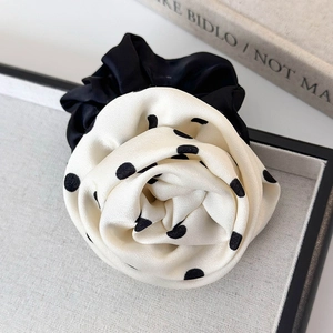 Détail d'un chouchou rose à pois noirs et blancs avec une texture satinée élégante