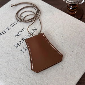 Close-up of a brown leather bell clochette key case with white stitching details