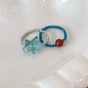 Detailed macro view of mint green starfish beaded rings set on a white ceramic plate
