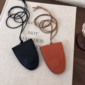 Detail view of lychee texture faux leather clochette charms in black and caramel colors