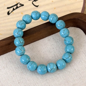 Gros plan d'un bracelet en perles de turquoise avec textures naturelles sur bois