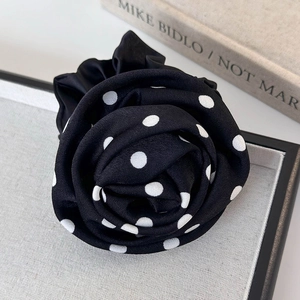 Détail d'un chouchou à pois noirs et blancs en forme de rose pour les cheveux