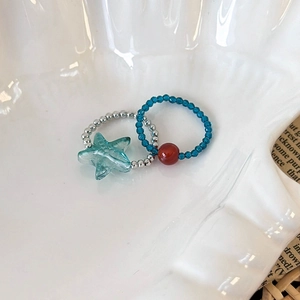 Detail of beaded ring set with starfish charm and navy faceted beads on shell tray