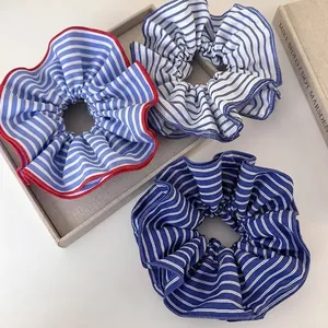 Trois grands chouchous en tissu à rayures bleues et blanches sur un plateau