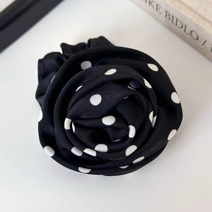 Gros plan détaillé d'un chouchou rose à pois noirs et blancs avec une texture en soie