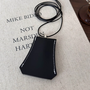 Detail showing black faux leather key bell clochette with white contrast stitching and cord