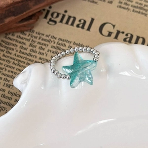 Detailed close-up of a silver beaded ring featuring a translucent mint green starfish